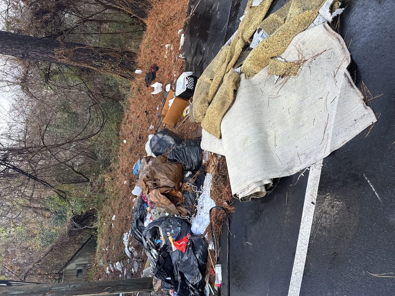 Parking lot covered in garbage bags, carpet rolls, and debris — before Junk Doctors