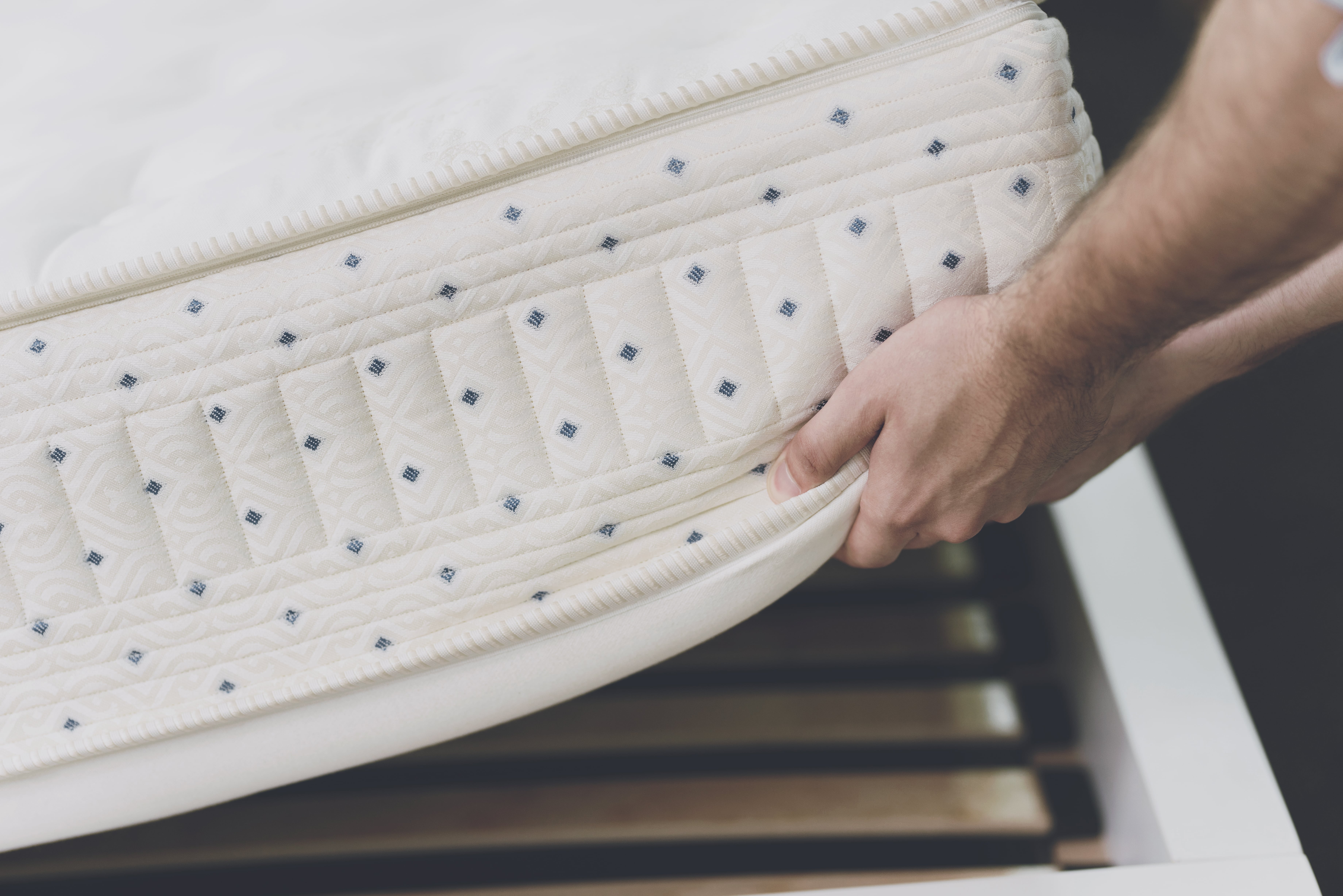 A man lifts his mattress up from his bed frame