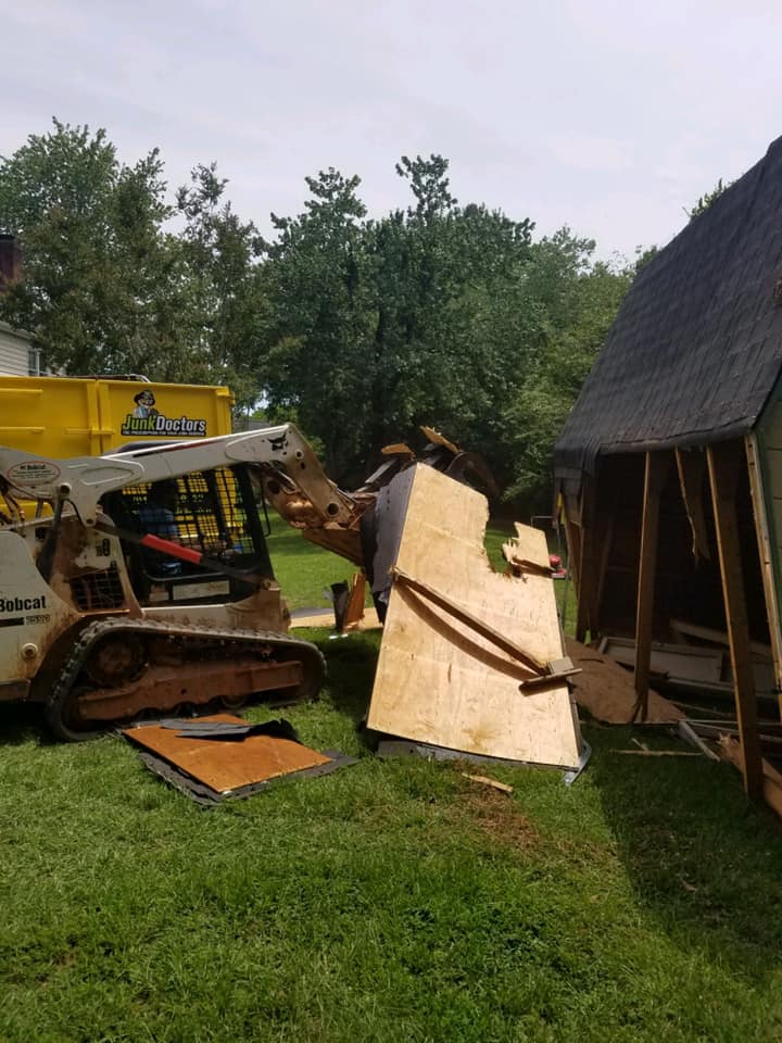Junk Doctors professional using heavy machinery to demolish an old shed during demolition services in Mount Holly, NC