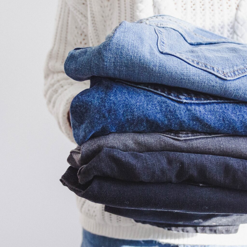 Person holding jeans ready to donate them instead of dumping them